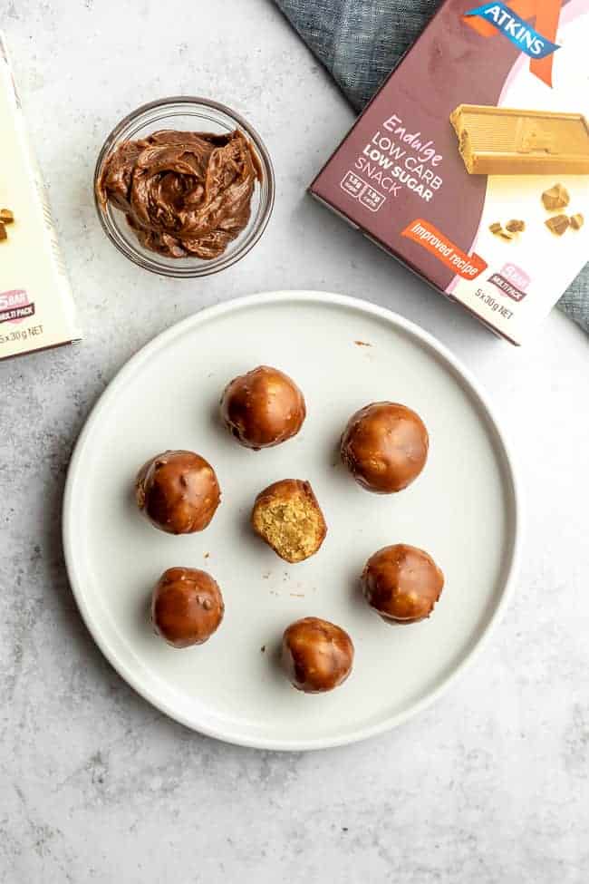 low carb peanut butter balls with swirl of chocolate on grey background with box in top corner